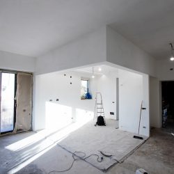 Apartment under renovation with building material and building dust. Plaster carton and test lighting, windows with cardboard and electric wires to be covered. Building renovation for a loft